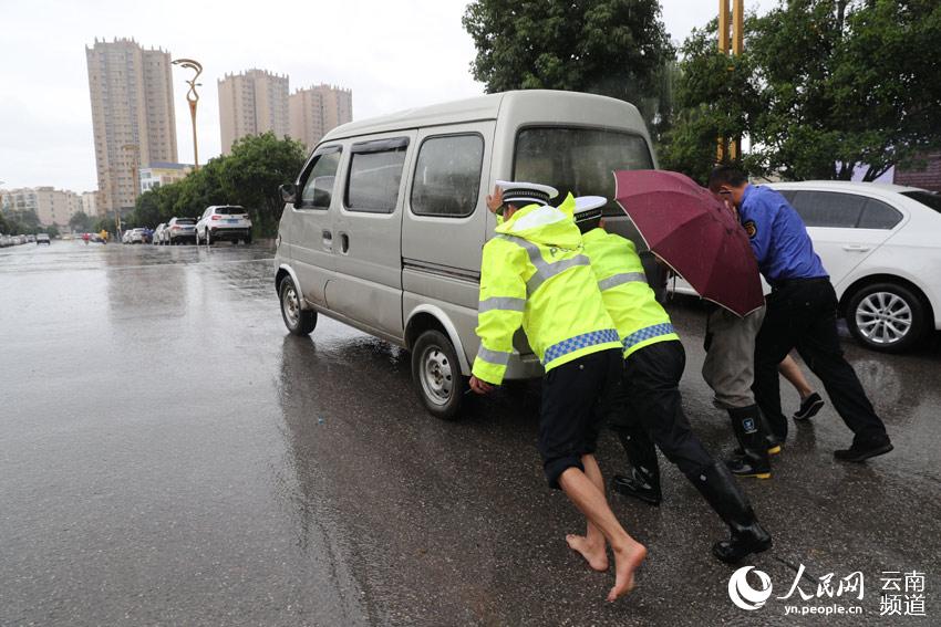 市民抓拍!云南昭通"赤脚交警"冒雨帮市民推车