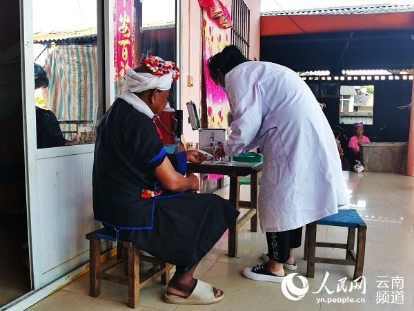 家庭醫生唐雅仙上門為德昂族老人李臘拽測量血糖。（人民網 劉怡 攝）