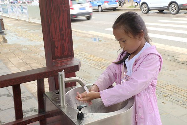 一個小女孩在路邊的洗手池裡洗手（供圖）
