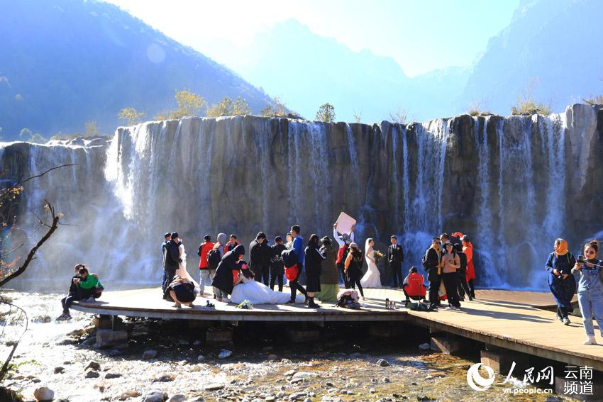景區瀑布前，新人排隊拍攝婚紗照。（人民網 符皓 攝）
