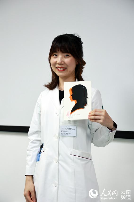 医护人员展示剪纸艺术家现场为其剪裁的肖像剪纸。人民网 徐前摄