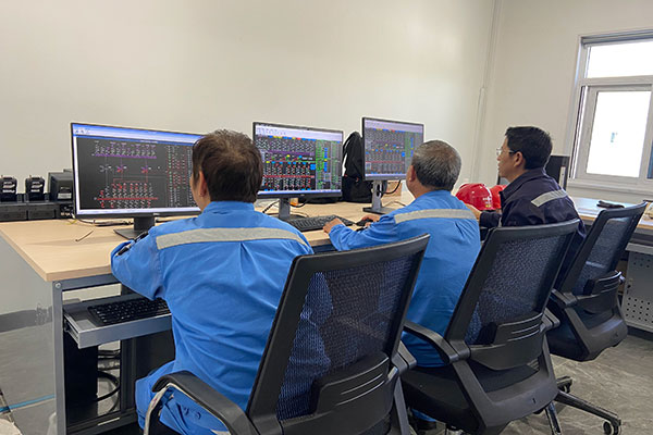 三岔變電站主控室內工作人員查看后台監控機。