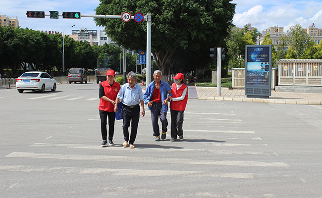 志願者扶老人過馬路。蒙自市融媒體中心供圖