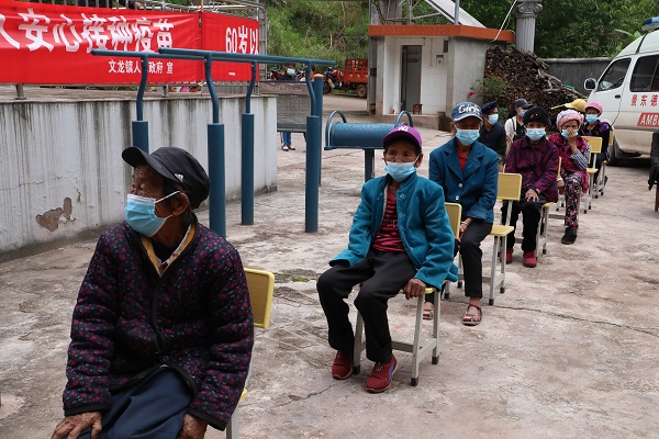 老年人坐在凳子上排隊等待接種疫苗。景東縣融媒體中心供圖