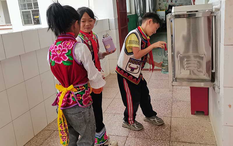 五台完小学生正在使用“暖冬行动”捐赠的热水器接热水。周朝枝摄