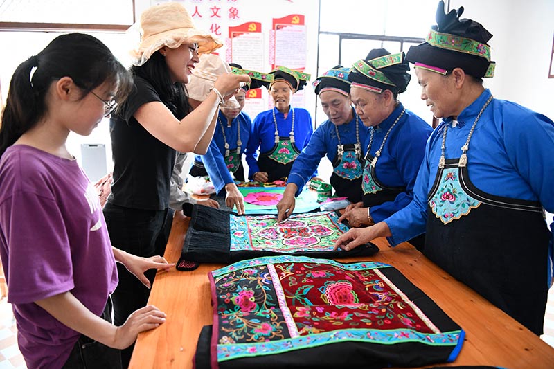 小寨村刺绣队在给游客介绍壮族背带。