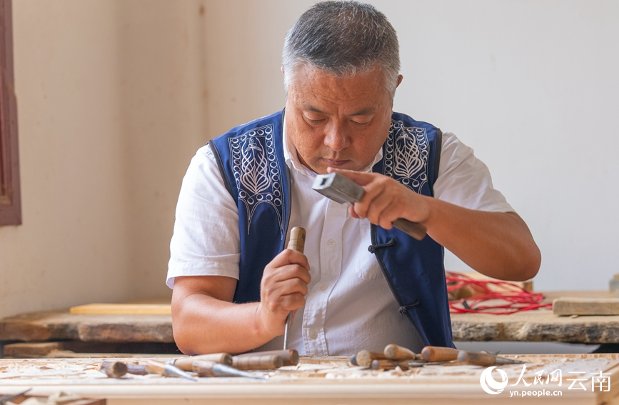 劍川木雕國家級非遺代表性傳承人段四興正在雕刻作品。人民網 虎遵會攝