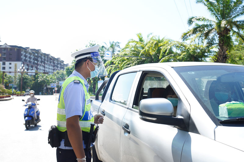 民警頂著烈日在路口查驗過往車輛。