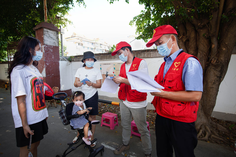 在小區門口做志願服務的檢察干警核查出入群眾核酸檢測情況。
