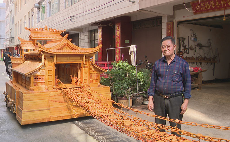 普明才和他的木雕作品《飛奪瀘定橋》。郭雨晨攝