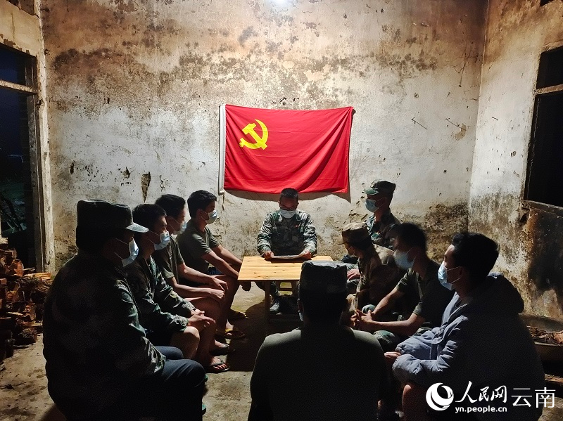 图二 在简陋的党员活动室内，前哨排临时党支部的党员们围坐在党旗下开会、学习。（受访者供图）