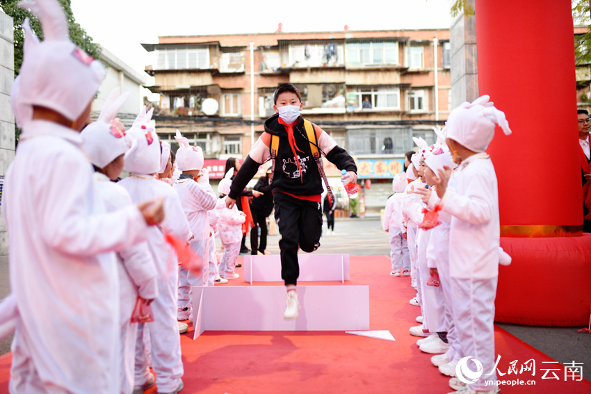 2月13日,昆明市官渡区东站实验学校老师带着“兔宝宝”们在学校门口迎接同学们。王正鹏摄