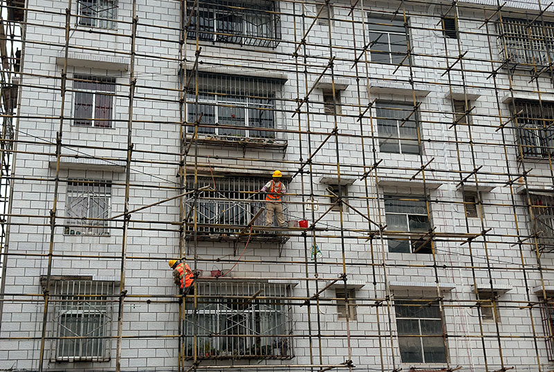 勐烈镇住宿区内工人正在进行墙体修复。