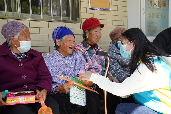 青年團員楊晴（右一）給老人們發放愛心物資。李春瑤攝