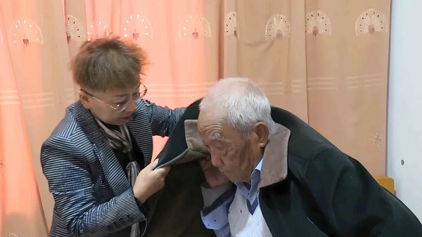 李红艳帮公公穿衣。景东县融媒体中心供图