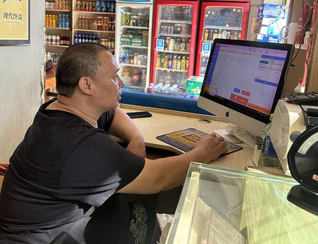 黄昌国在查看店内商品库存。曾俊摄