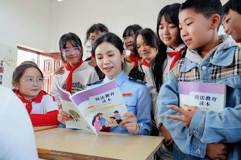 在个旧市乌谷哨小学,税务“老师”利用《税法教育读本》等学习资料,带领同学们图文并茂地学习税收知识。(高元庆-摄)