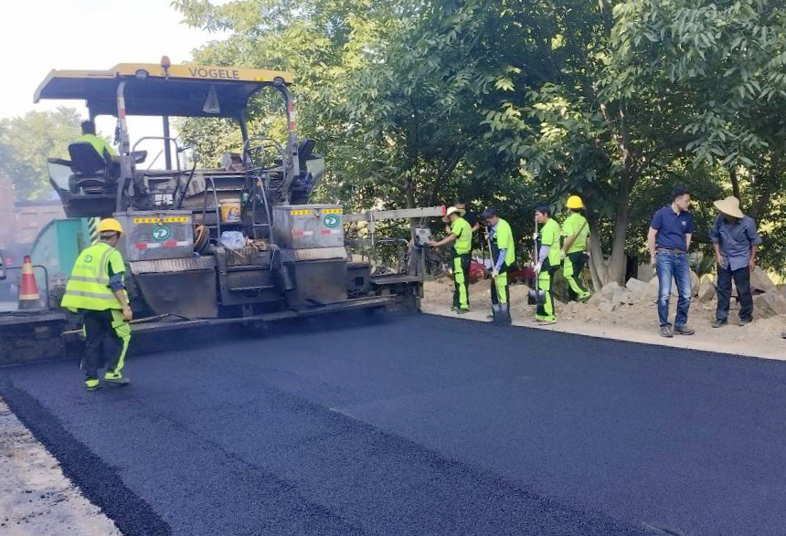 小忙兔村入村主干道路沥青路面铺设作业。谢华剑摄