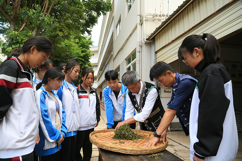 李明泽（右二）跟随父亲李兴昌在宁洱县职业高级中学向学生传授普洱茶·贡茶制作技艺。宁洱县融媒体中心供图