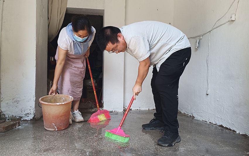 个旧市烟草专卖局工作人员（左）帮助侬沛鸿打扫店面卫生。罗芸摄