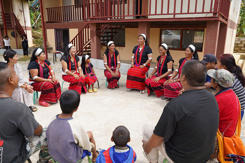 永老寨村民围坐在一起学唱《学习小新寨》。李毅摄