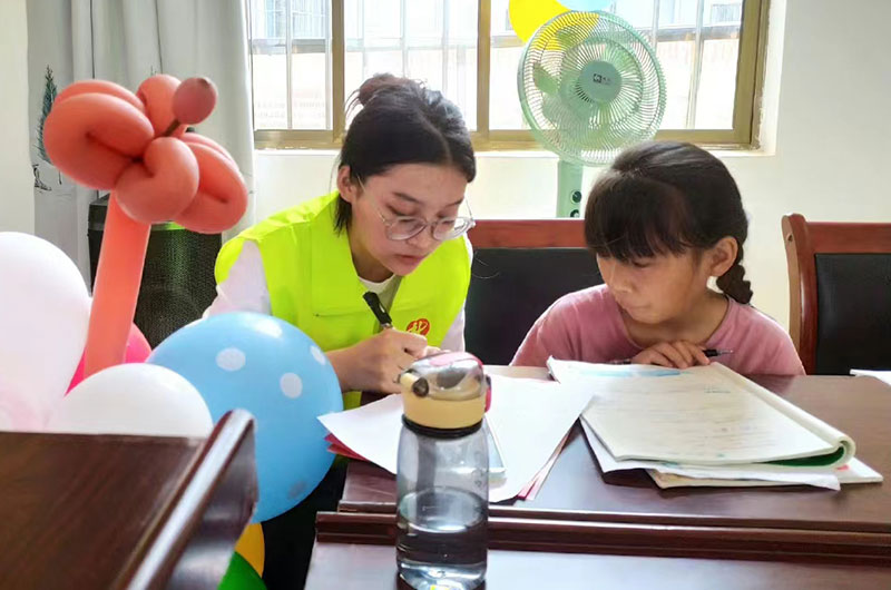威远镇大学生志愿者为留守儿童辅导课业。