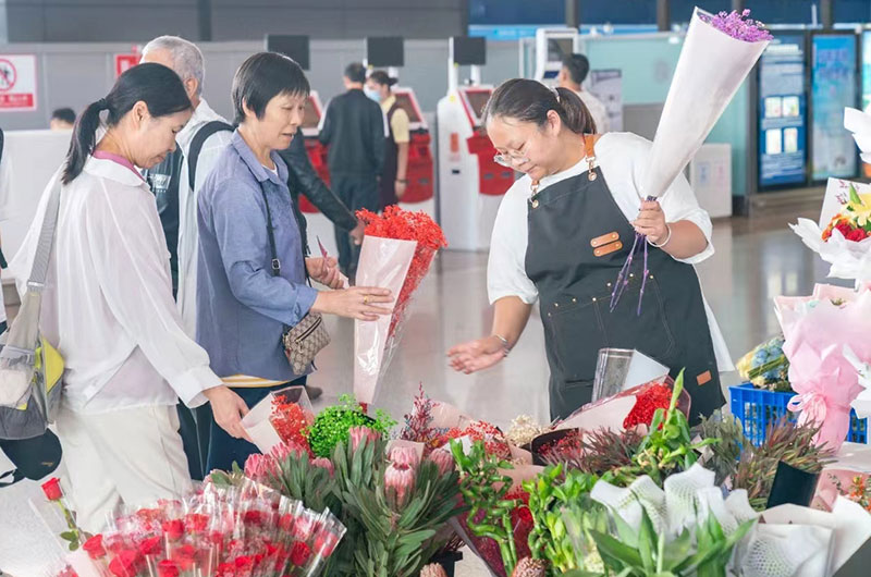 昆明机场航站楼内过往旅客购买鲜花。尚震摄