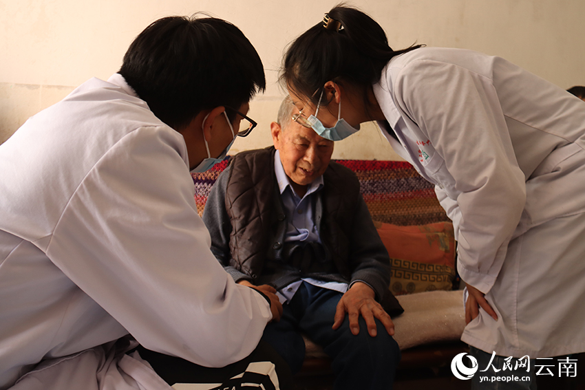 官渡區醫養結合服務人員朱密朵和潘飛正在為張光林老人做健康監測和康復理療。人民網 曾智慧攝