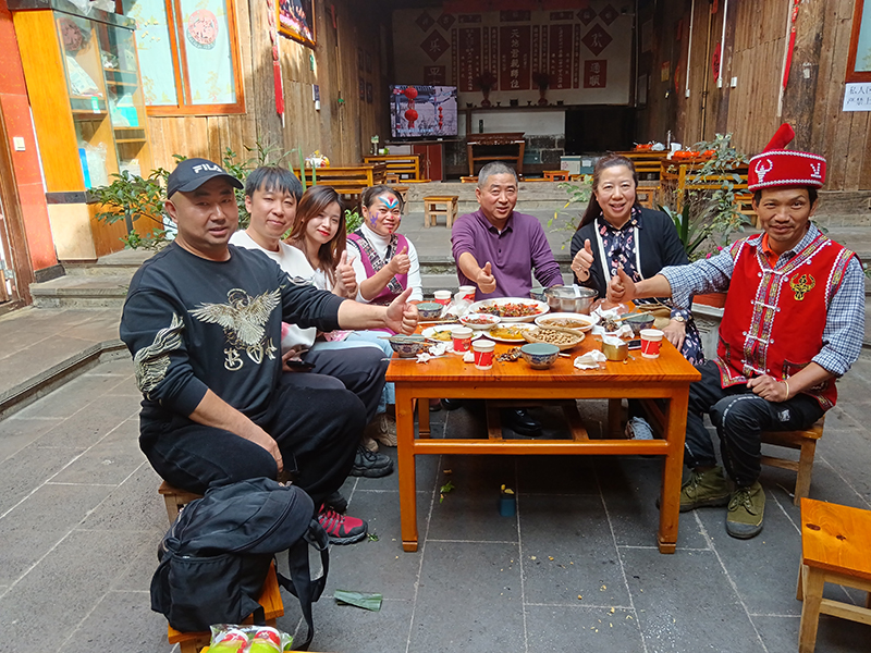 李發順（右一）和妻子（左四）與游客圍桌而坐，幸福的笑容在他們的臉上綻放。受訪者供圖