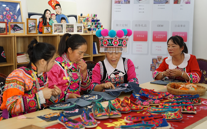 张琼芬（右二）正在指导绣娘刺绣。大姚县融媒体中心供图