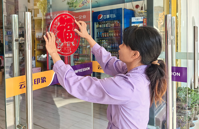 朱艳凤为小店张贴窗户营造浓厚节日氛围。王奕清摄