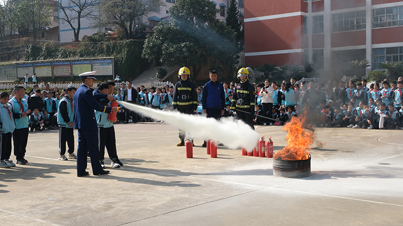 学生在消防员的指导下现场实操使用灭火器。