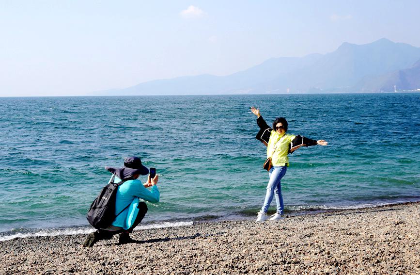 游客在抚仙湖畔拍照。杨朔摄