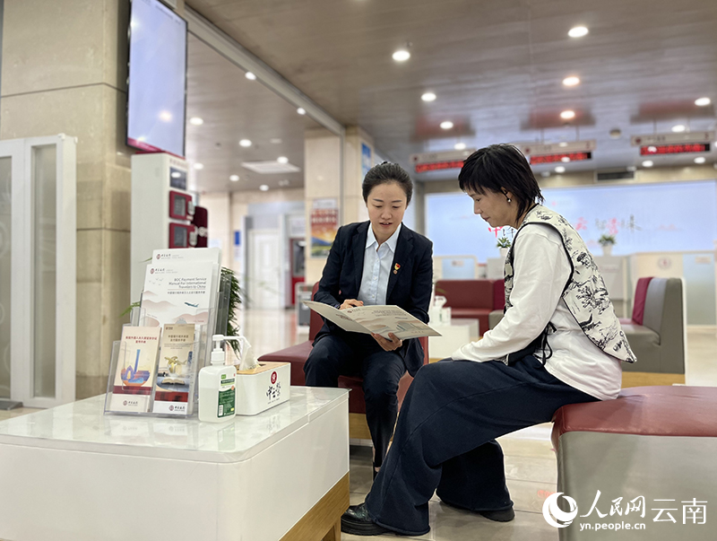 【图1】中国银行云南省分行工作人员向客户介绍“云岭创业贷”的申请条件。人民网-尹馨摄