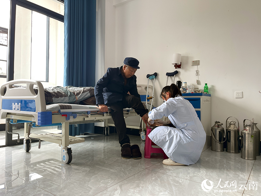 在漾濞县中心敬老院，护工给一名老年人敷药。人民网记者 程浩摄