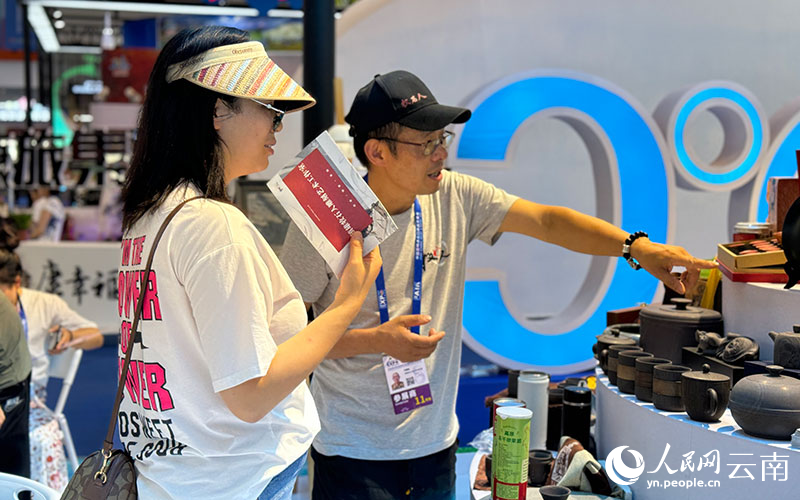 南博会昭通展区工作人员为游客介绍文创产品。人民网记者-蔡树菁摄