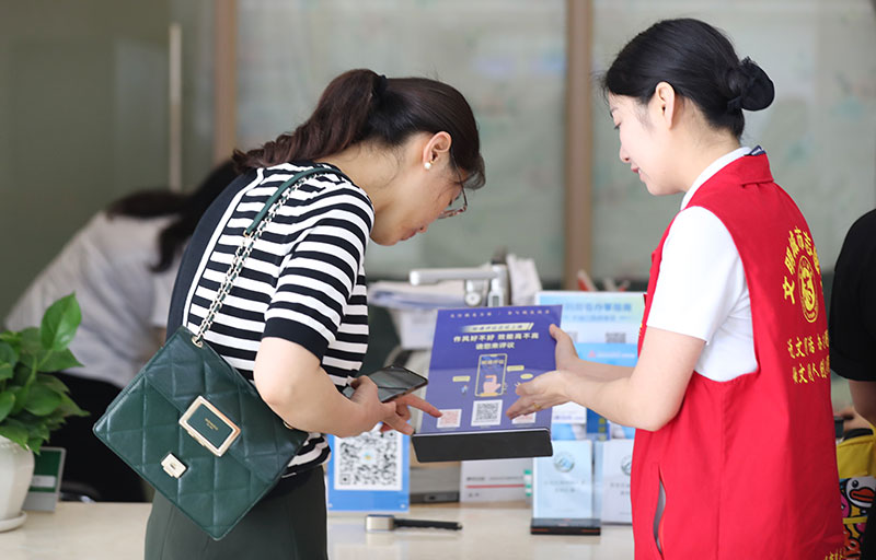 圖為2023年7年10，市直機關黨員干部主動引導辦事群眾掃碼評議機關作風。