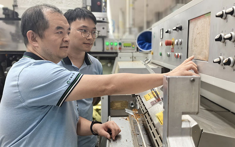 王海洋(前)教徒弟查阅、调整设备参数。姜竣琳摄