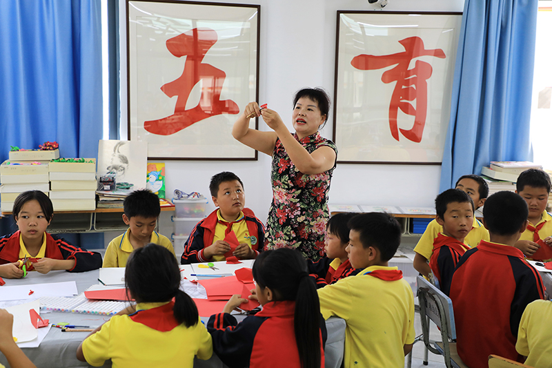 春荣正在教学生剪纸。杨佳燕摄