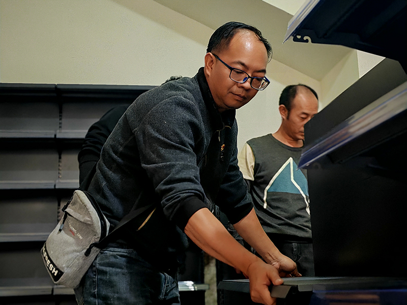 西畴县烟草专卖局党员志愿者正在帮助冯在元搭建商品货架。