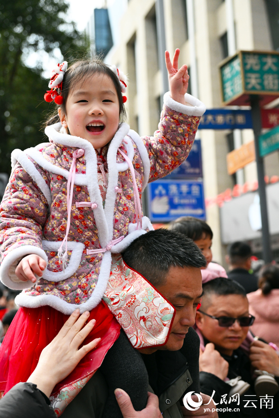 1月29日，大年初一，一位小朋友在云南省文山市步行街观看民俗表演。熊平祥摄