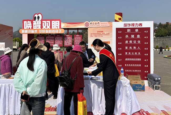 （3月13日，曲靖市“守护金融权益，‘靖’享美好生活”活动互动游戏现场，工作人员向来往群众讲解金融知识，拍摄人：唐金娥）1