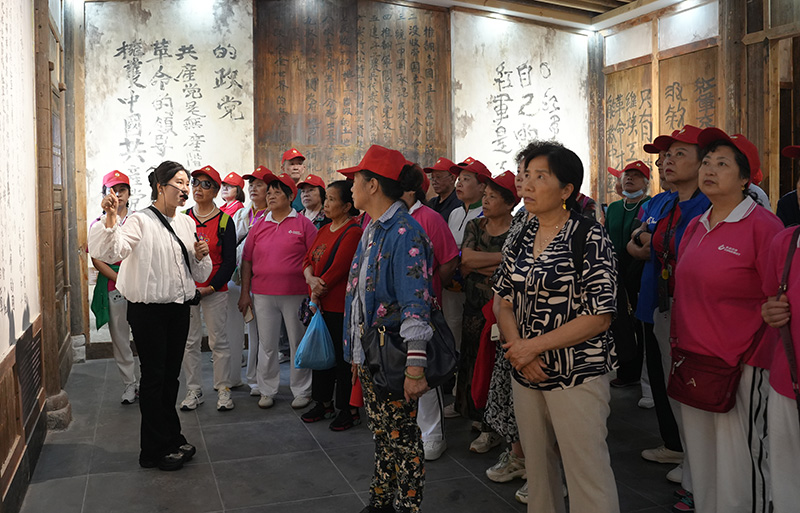 2025年6月25日摄，旅游团参观红军长征标语馆，认真聆听讲解员讲解