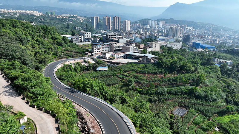蓝天白云下，溪洛渡通三级公路蜿蜒向群山绵延伸展。2025年7月4日摄。