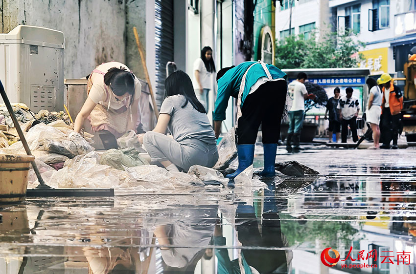 暴雨过后，威信县的干部群众纷纷走上街头，齐心协力开展清淤清障、商品货物清洗等工作。人民网 尹馨摄