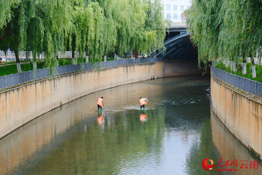 兩名環衛工人正在清理城市河道裡的雜物。曾智慧攝