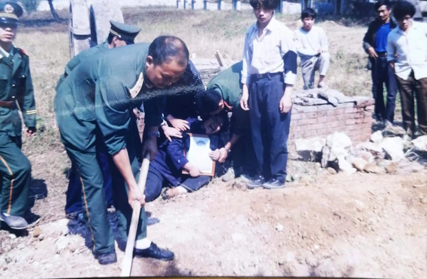 【图3】图为1993年4月毛炜烈士下葬时现场，母亲杨爱玲抱着毛炜遗照痛哭。