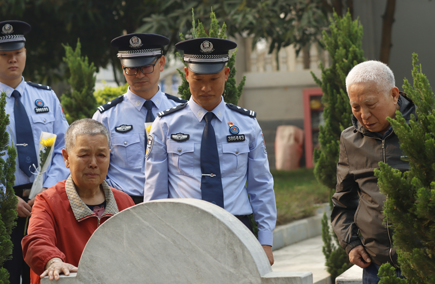 【图13】图为2025年4月3日，民警和烈士家属在毛炜烈士碑前，母亲杨爱玲正在擦拭墓碑。