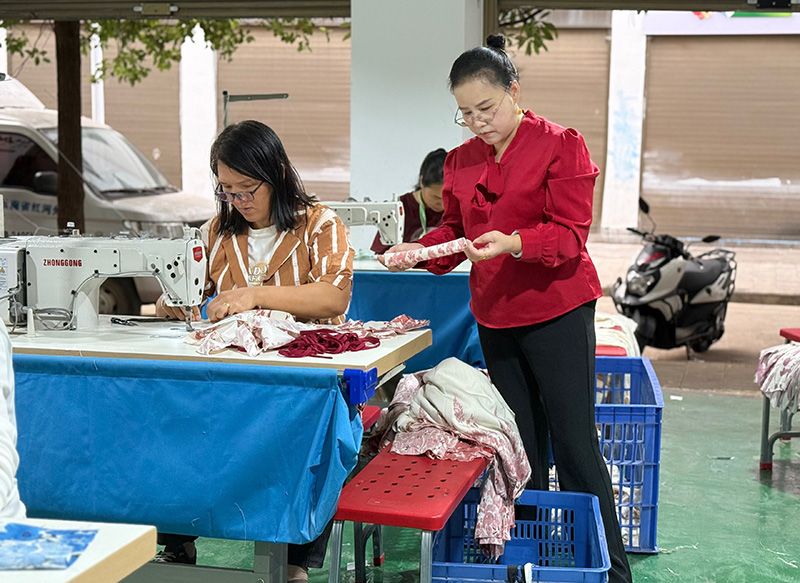 红河县美兰服饰有限公司加工厂负责人陆美电在查看产品质量