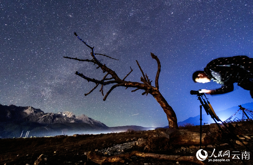 摄影师在玉龙雪山脚下与星空“对话”，枯木、人物与浩瀚银河相映成趣。卫楷文摄